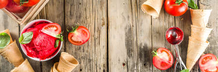 Vegetable gelato. Tomato ice cream with fresh tomatoes and basil and leaves, old rustic wooden background. banner formatの写真素材