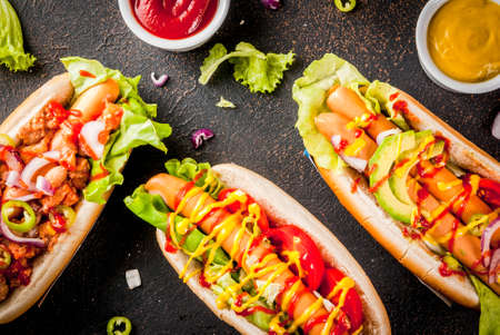Assortment of different homemade hot dogs with sausage, fried onion, tomatoes and beans, dark rusty background copy space top viewの写真素材