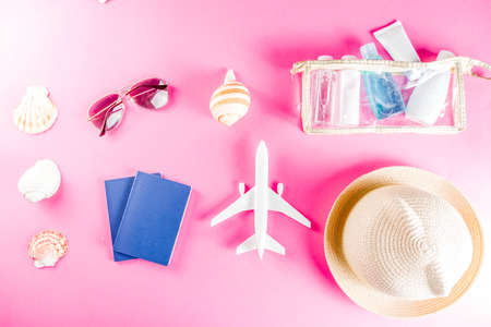 Travel and vacation flatlay concept. Summer bright colorful background with hat, sunglasses, plane,  passport, tropical leaves, travel cosmetics kit, seashells, copy space top view bannerの写真素材