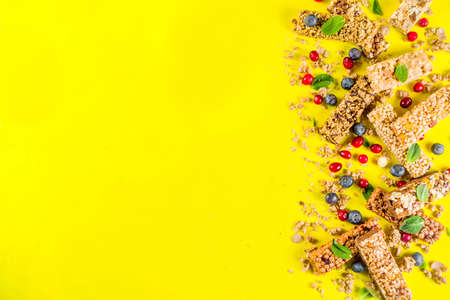 Cereal granola bars with nuts, fruits and berries, bright yellow background top view copy spaceの写真素材