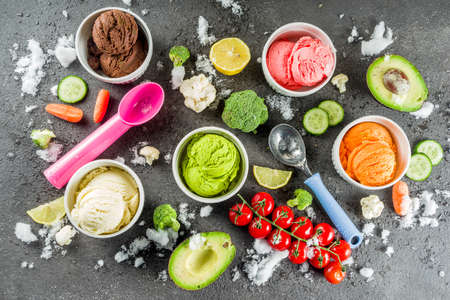 Trendy vegan food, summer healthy dessert concept, colorful diet vegetable ice cream with avocado, cucumber, tomato, beet, carrot, broccoli, cauliflower. Frozen veggie smoothie, black backgroundの写真素材