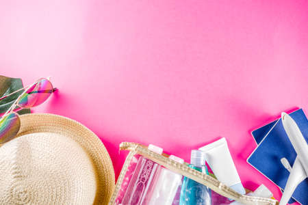 Travel and vacation flatlay concept. Summer bright colorful background with hat, sunglasses, plane,  passport, tropical leaves, travel cosmetics kit, seashells, copy space top view bannerの写真素材