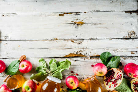 Jewish Autumn Rosh Hashana celebration. Traditional products for the celebration of Rosh Hashanah - apples with leaves, pomegranate, honey, honeycombs, white wooden  backgroundの写真素材