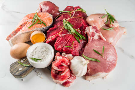 Carnivore diet background. Non vegan protein sources, Different meat food - chicken breast, pork steak, beef tenderloin, eggs, spices for cooking. White marble background copy spaceの写真素材