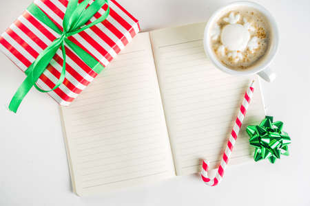 Preparation for Christmas background with gifts box, xmas decoration, coffee cappuccino cup and clear notepad for wishes, gift list or to do list. Top view flatlay copy spaceの写真素材