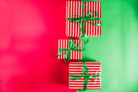 Christmas gift boxes simple pattern background. Festive boxes with Christmas presents, decorated with bright bows with ribbons. Flatlay, above copy spaceの写真素材