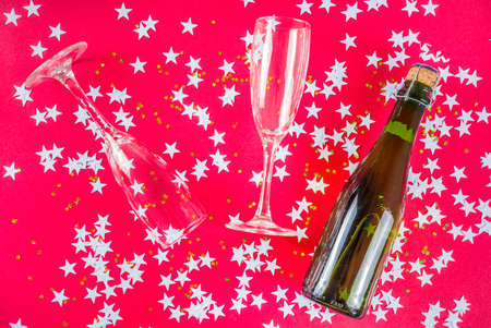 New Year and Christmas holiday layout. Trend bright pink background with glasses and a bottle of...
