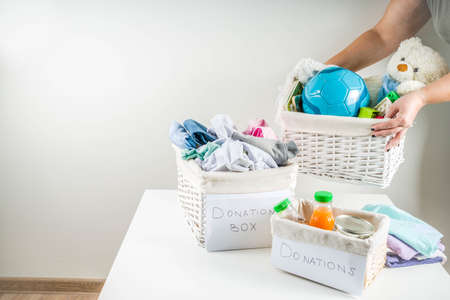 Giving and helping concept. Reuse and recycling theme. Donation box with clothes, children's toys, food. On a white backgroundの写真素材