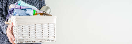 Giving and helping concept. Reuse and recycling theme. Woman holds and folds donation box with clothes, children's toys, food. On a white background, Girl's hands in pictureの写真素材