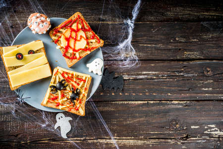 Funny Halloween sandwiches for kids breakfast. Child Halloween party food concept. Old rustic wooden background copy space top viewの写真素材