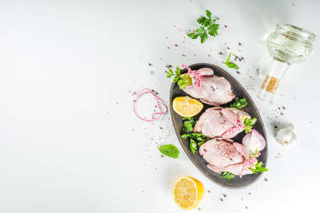 Cooking healthy diet lunch concept. Three whole quails with spices, herbs, vegetables, olive oil, for cooking on a black stone concrete table copy spaceの写真素材