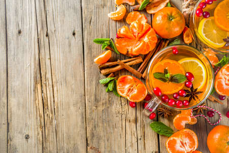 Autumn winter spicy hot citrus tea with tangerines, cranberries, honey and spices. On a wooden...