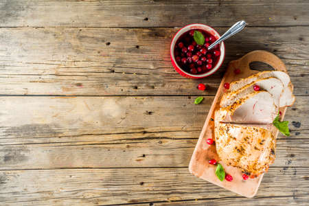 Traditional Thanksgiving autumn dish. Baked turkey breast fillet with cranberry sauce, on a cutting board wooden rustic background copy spaceの写真素材