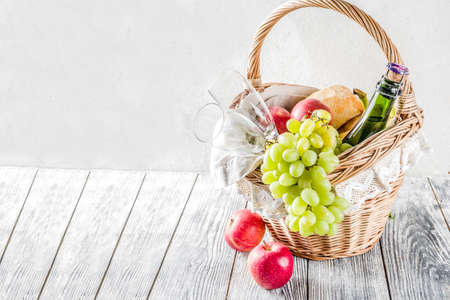 Picnic basket with food and drinks (fresh fruits, bread and wine bottle, glasses), copy spaceの写真素材