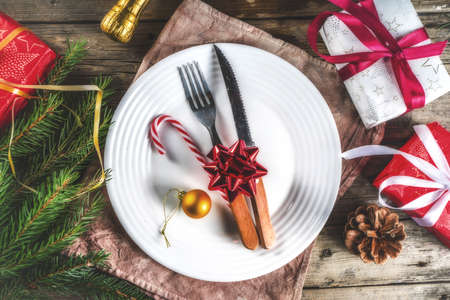 Christmas festive table setting with with a plate, fork, Christmas decorations, gift boxes, fir tree branches, glass and champagne bottle. Holiday table background copy spaceの写真素材
