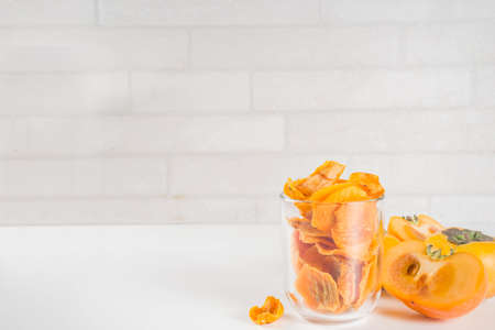 Dried persimmon fruit, with fresh persimmons, on white concrete or stoneの写真素材