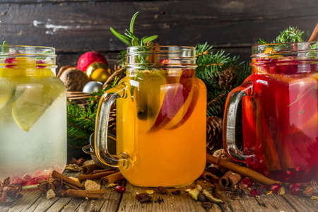 Autumn winter sangria, mulled wine or hot spiced cider cocktails. Red, white and orange hot winter drinks and beverages, in glass mason jar mugs with spices and citrus fruit. Om Christmas decorated rustic background copy spaceの写真素材