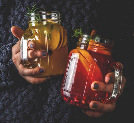 Autumn winter sangria, mulled wine or hot spiced cider cocktails. Red, white and orange hot winter drinks and beverages, in glass mason jar mugs with spices and citrus fruit. Decorated rustic background copy spaceの写真素材