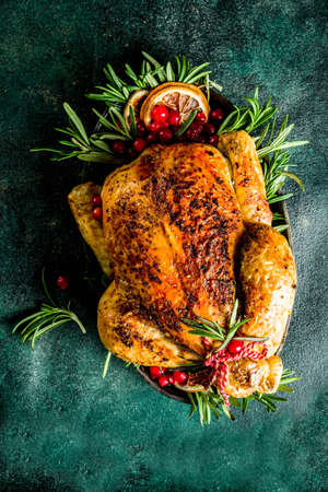 Traditional Christmas and Thanksgiving roasted whole chicken with fruit and rosemary. Dark green concrete table top view copy spaceの写真素材