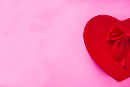 Woman hands holding Valentine's Day gift box on pink trendy background. Top view with copy space