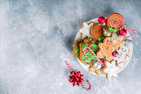 Homemade christmas sugar and gingerbread cookies decorated with colorful icing on grey stone background with Christmas tree branches and decorationsの写真素材