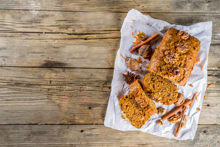Homemade carrot cake with walnuts, rustic wooden background with ingredients, copy space