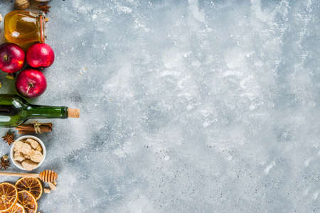 Mulled wine recipe ingredients on grey stone background. Christmas winter warming drink cooking - wine bottle, honey, orange, cinnamon, anise, nutmeg, cloves, sugarの写真素材