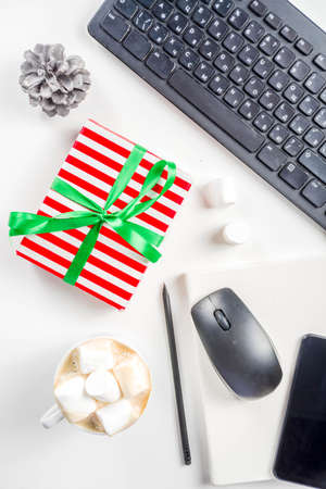 Office secret santa concept with Office table surface, keyboard, mouse, gift boxes and Christmas decoration whiteの写真素材
