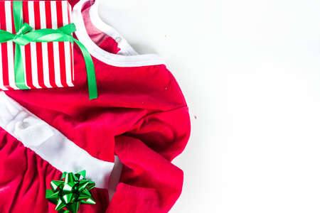 Christmas preparation concept. Christmas dress Santa Claus for girl, with santa's hat and New Year's gifts. On a white background, top view flat lay copy spaceの写真素材