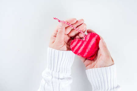Red textile heart in girls hands from above. Valentines day card. Giving love concept with woman hands hold red heart. Healthy, love, donation organ, donor, hope and cardiology backgroundの写真素材