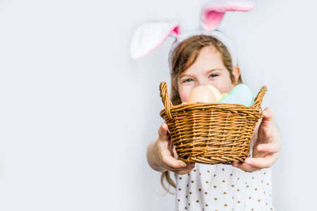 Happy cute child girl in rabbit costume with bunny ears holds basket painted eggs in handsの写真素材