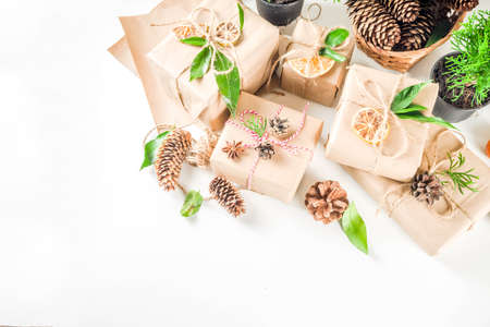 Zero waste christmas concept. Stack of handmade christmas gift boxes in craft paper with  different organic decoration and little live xmas tree in flowerpots. の写真素材