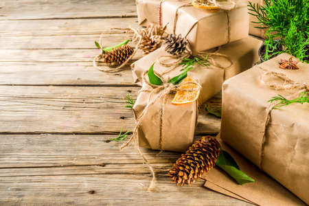 Zero waste christmas concept. Stack of handmade christmas gift boxes in craft paper with  different organic decoration and little live xmas tree in flowerpots.の写真素材