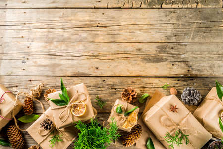 Zero waste christmas concept. Stack of handmade christmas gift boxes in craft paper with  different organic decoration and little live xmas tree in flowerpots.の写真素材