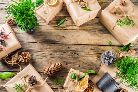 Zero waste christmas concept. Stack of handmade christmas gift boxes in craft paper with  different organic decoration and little live xmas tree in flowerpots.の写真素材