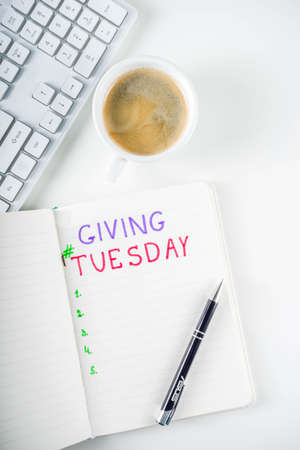 Notepad for To-Do list Giving Tuesday. White paper ready to write notes to various helping on Tuesday. International Charity Aid Day, giving hashtag activity. On a white desktop flatlay copy spaceの写真素材