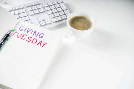 Notepad for To-Do list Giving Tuesday. White paper ready to write notes to various helping on Tuesday. International Charity Aid Day, giving hashtag activity. On a white desktop flatlay copy spaceの写真素材