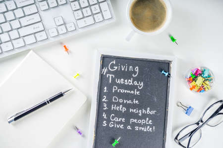 Chalk board with list of tasks, ideas, task for Giving Tuesday. Notes to various helping on Tuesday. International Charity Aid Day concept. White desktop flatlay copy spaceの写真素材
