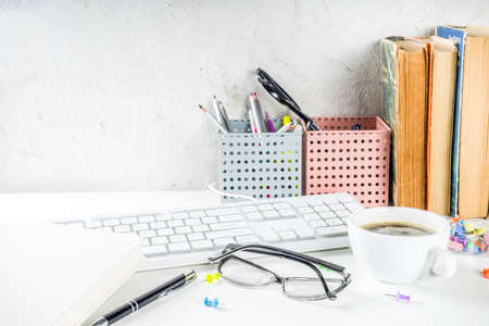Office creative desk with supplies and coffee cup. White office table with keyboard, blank notebook, glasses, supplies and coffee cup. Flatlay layout copy space top viewの写真素材