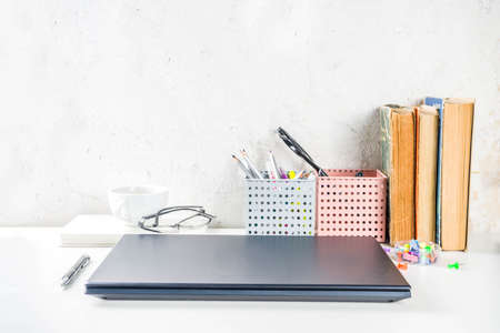 Office creative desk with supplies and coffee cup. White office table with laptop, keyboard, blank notebook, glasses, supplies and coffee cup. Flatlay layout copy space top viewの写真素材