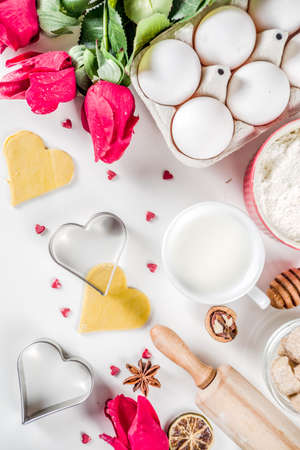Valentine day baking background. Ingredients for cooking Valentine's heart cookies. Flour, eggs, sugar, spices on wooden background with red flower roses. Top view copy space.の写真素材