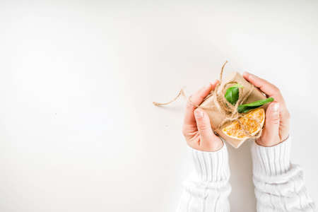 Woman hands holds christmas gifts. Female hands with rustic decorated gift boxes, in craft paper and organic decorations. Top view copy spaceの写真素材