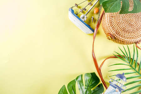 Summer vacation background. Tropical leaves, wicker bag, summer accessories and decorations. Yellow background top view flat layの写真素材