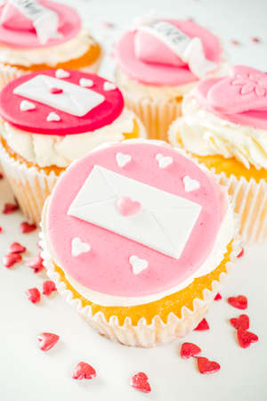 Valentine's day greeting card. Sweet Valentine's creative dessert food. Homemade pink and red  delicious cupcakes with decor of Valentine day symbolsの写真素材