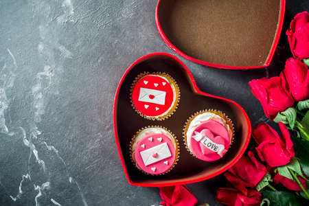 Valentine's day greeting card. Sweet Valentine's creative dessert food. Homemade pink and red  delicious cupcakes with decor of Valentine day symbolsの写真素材