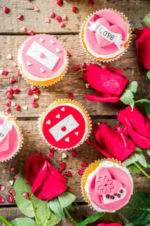 Valentine's day greeting card. Sweet Valentine's creative dessert food. Homemade pink and red  delicious cupcakes with decor of Valentine day symbolsの写真素材