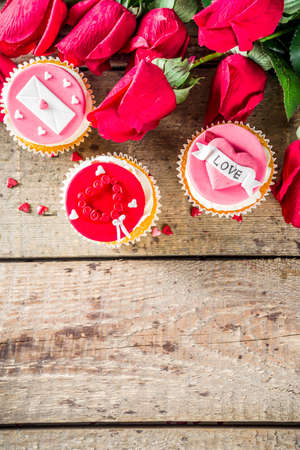 Valentine's day greeting card. Sweet Valentine's creative dessert food. Homemade pink and red  delicious cupcakes with decor of Valentine day symbolsの写真素材