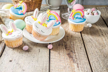 Easter holiday greeting card background. Cute homemade cupcakes with traditional Easter bunny, egg and springtime flowers decor. Happy easter concept. Copy space for your textの写真素材