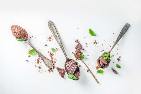 Different conditions of cocoa. Various cocoa - beans, beans, ground, crushed cocoa powder, chocolate paste, chocolate pieces and hot chocolate in a cup. In various spoons, white background aboveの写真素材