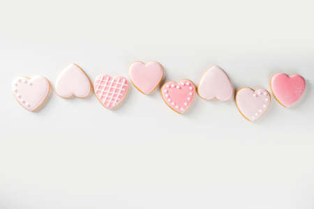 Homemade pick sugar glazed Valentine day cookies. Valentine heart shaped bakings. White stone background copy space top viewの写真素材